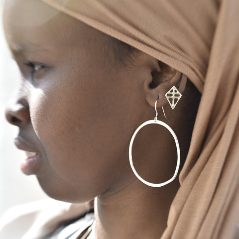 Close-up of a person wearing a headscarf with earrings visible.